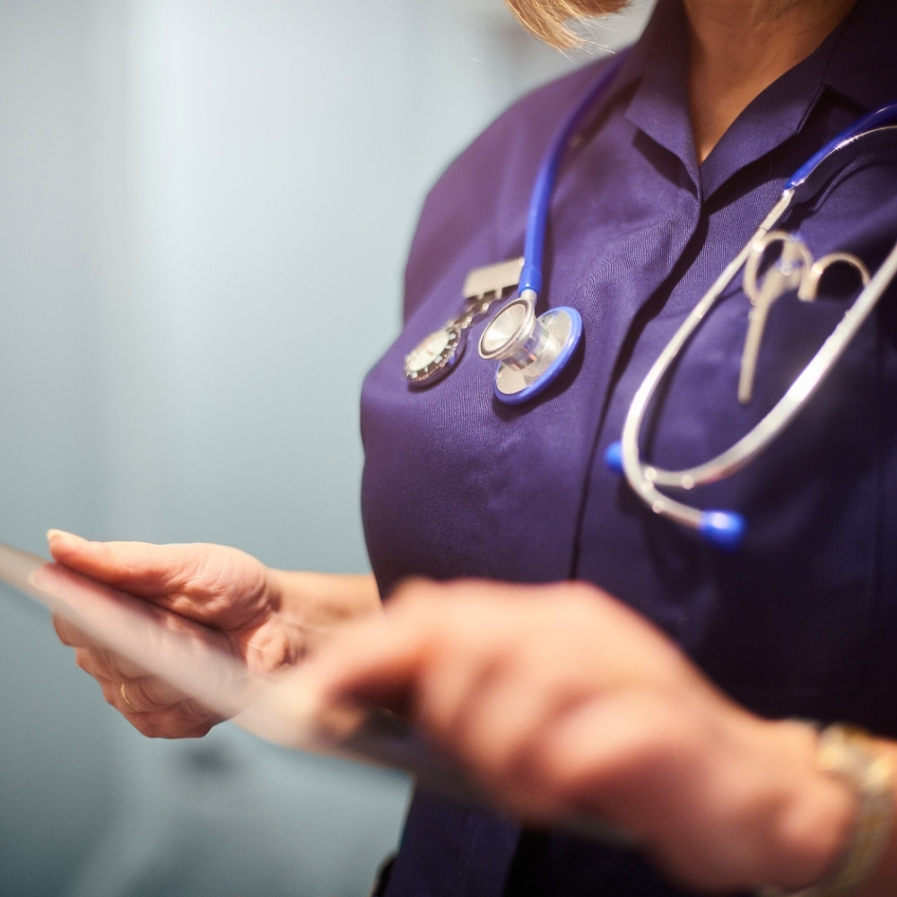 eine person aus dem gesundheitssystem zeigt etwas auf dem tablett zur digitalisierung im gesundheitssystem