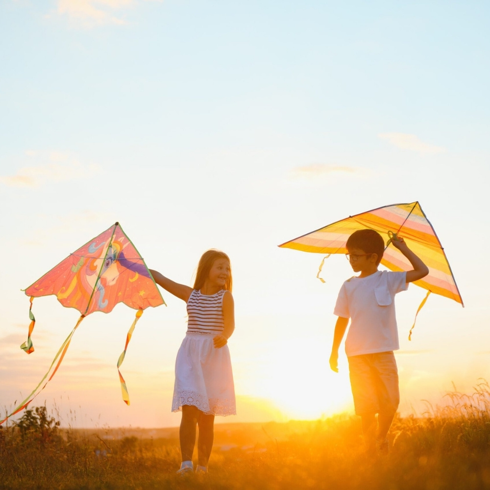 zwei kinder lassen ihre drachen steigen im sonnenuntergang