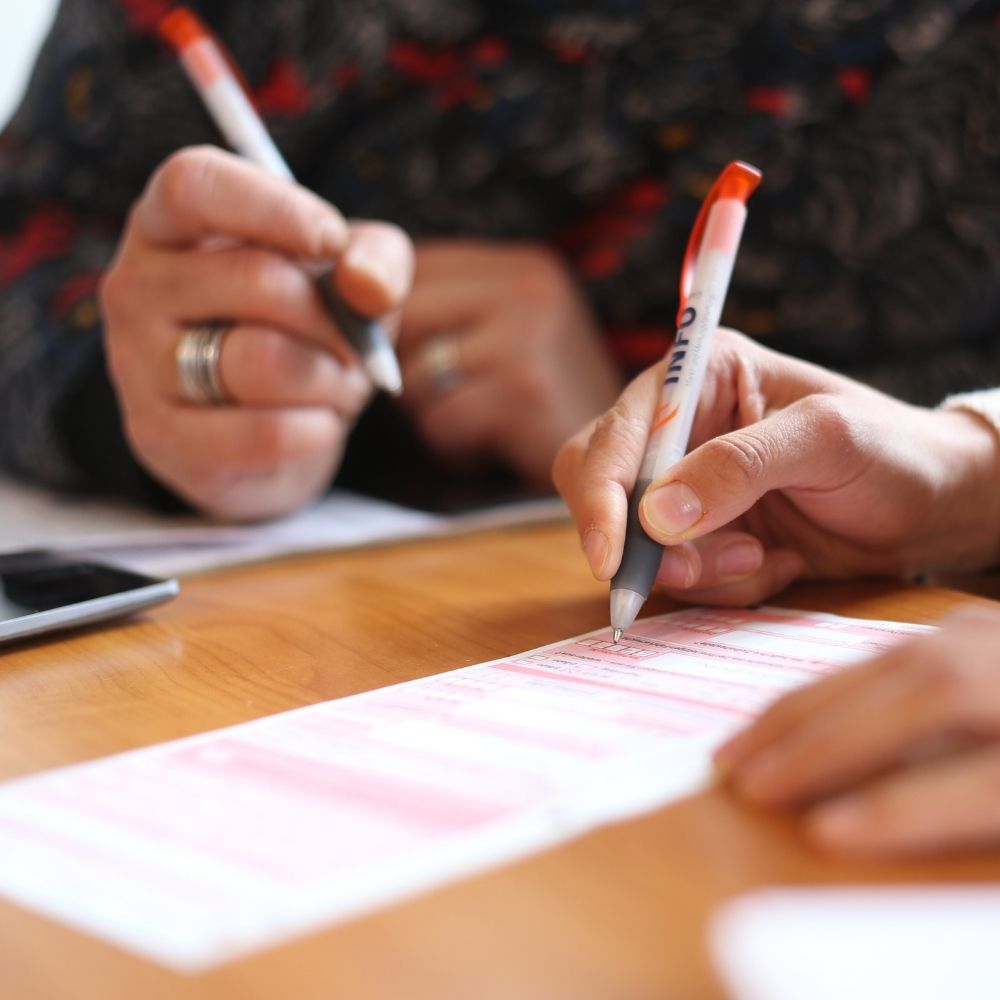 zwei personen füllen ein formular aus - beide halten einen kugelschreiber in der hand