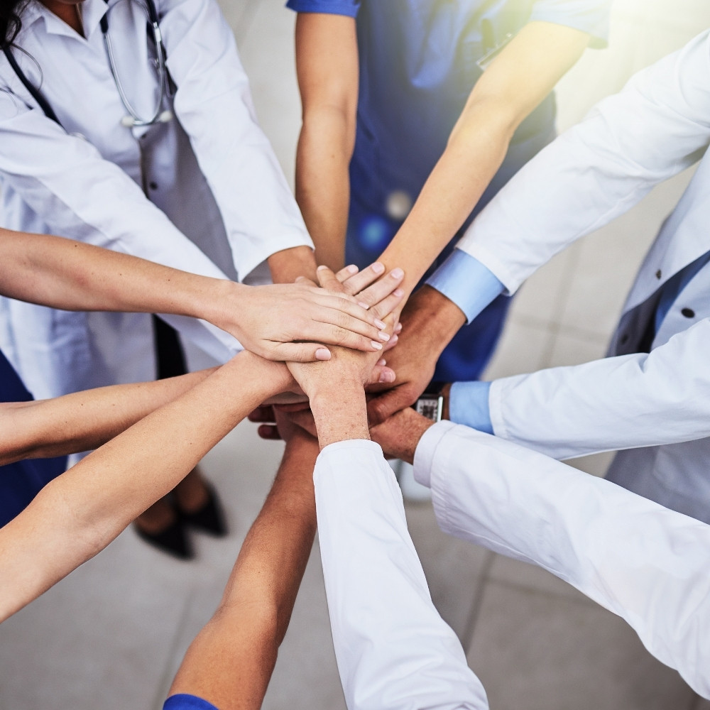 eine gruppe menschen legt die hände übereinander - ein team - wir liefern antworten